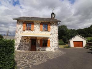 a small stone house with orange shuttered windows at Gîte Vic-sur-Cère, 3 pièces, 4 personnes - FR-1-742-354 in Vic-sur-Cère