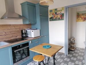 cocina con armarios azules y mesa de madera en Guestroom Briare, 1 pièce, 2 personnes - FR-1-590-369, en Briare