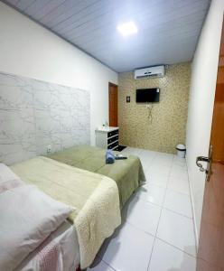 Schlafzimmer mit einem Bett und einem Flachbild-TV in der Unterkunft Napolitan House in Manaus