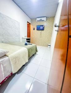 1 dormitorio con 1 cama y TV en la pared en Napolitan House, en Manaus