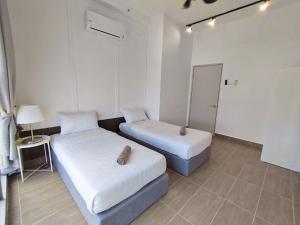 ein Zimmer mit zwei Betten und einem Tisch mit einer Lampe in der Unterkunft Troika Kota Bharu Penthouse Homestay 2 rooms in Kota Bharu + 6 Fotos