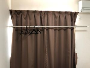 einen Duschvorhang mit drei Kleiderbügeln im Bad in der Unterkunft I・ecoⅢ（アイエコスリー） in Niigata