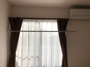 ein Fenster mit Vorhang in einem Zimmer in der Unterkunft I・ecoⅢ（アイエコスリー） in Niigata