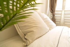 a bed with white pillows and a plant on it at AG 3 Sun Sand and serenity intimate in Nice