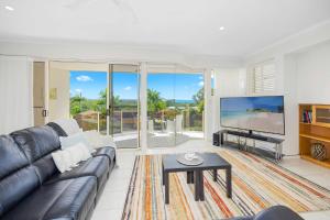 a living room with a couch and a large screen tv at Paradise View @ Bonny Hills in Bonny Hills