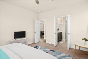 a white bedroom with a bed and a tv at RoundRockLuxuryLivingW/GameRoom in Round Rock