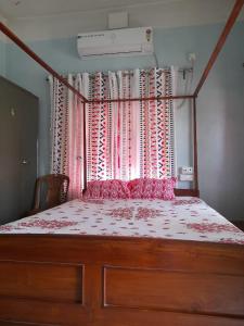 a bedroom with a large bed with a window at Balurghat Hotel KOKORO Farmhouse in Bālurghāt