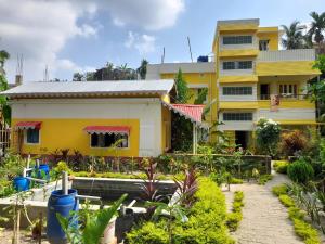 ein Haus mit Garten davor in der Unterkunft Balurghat Hotel KOKORO Farmhouse in Bālurghāt