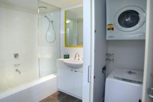 a bathroom with a shower sink and a washing machine at Quest on Dorcas in Melbourne