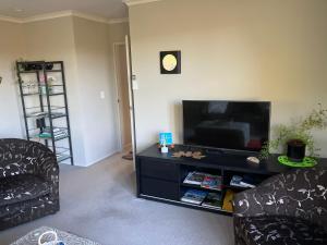 sala de estar con 2 sillas y TV de pantalla plana en Kingsley Quarters en Cambridge