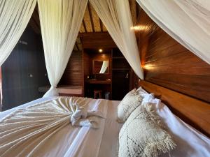 a bedroom with a bed with white sheets and curtains at Sunset Hill Lembongan in Nusa Lembongan