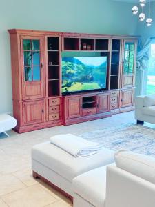 een woonkamer met een televisie in een houten entertainmentcentrum bij Large Luxury 4 Bed Guest House In King City in King City