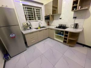 a kitchen with white tile floors and a refrigerator at Lovadek Spacious Apartment in Lagos