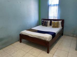 een klein bed in een kamer met een blauwe muur bij SPOT ON 93037 Nova Jaya Homestay Syariah in Lamongan