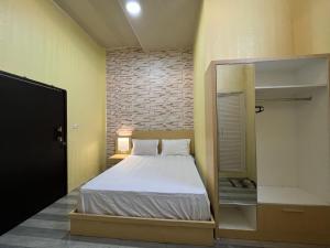 Dormitorio pequeño con cama y espejo en OYO 93052 Batodupi Guesthouse Syariah, 