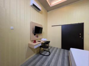 Camera con scrivania, TV e sedia. di OYO 93052 Batodupi Guesthouse Syariah 