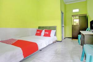 ein Schlafzimmer mit einem Bett mit roten Kissen darauf in der Unterkunft OYO 92998 Wiludjeng Guesthouse in Sragen
