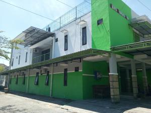 ein grün-weißes Gebäude mit einem Balkon in der Unterkunft OYO 93012 Griya Kencana Asri Syariah in Lawean