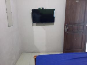 Zimmer mit einem TV an der Wand und einem Bett in der Unterkunft OYO 93012 Griya Kencana Asri Syariah in Lawean