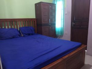 ein Schlafzimmer mit einem blauen Bett mit einem Holzrahmen in der Unterkunft OYO 93012 Griya Kencana Asri Syariah in Lawean