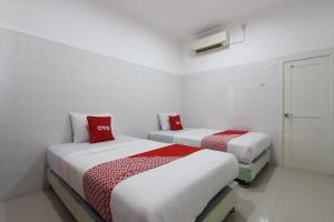two beds in a room with red pillows on them at OYO 93011 Hotel Griya Lestari Pati 2 in Pati