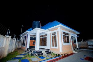 a small house with a blue roof at night at Niwa Apartments in Dar es Salaam