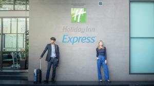 um homem e uma mulher de pé em frente a uma parede em Holiday Inn Express Bangkok Soi Soonvijai, an IHG Hotel em Banguecoque