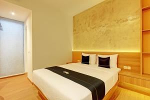 1 dormitorio con 1 cama grande con almohadas blancas y negras en Capital O 92987 Keenan Living Perumnas en Yogyakarta