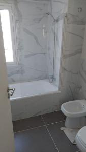 a white bathroom with a shower and a toilet at Calidez, confort y relax. in Trelew