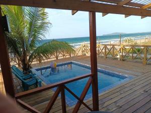 a swimming pool on a deck next to the beach at Villa Devonia - Beachfront Cabins with Pool at Tela, HN in Tela