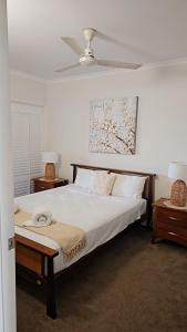 Airlie Seaview Apartments في شاطئ إيرلي: غرفة نوم بسرير مع مروحة وطاولتين