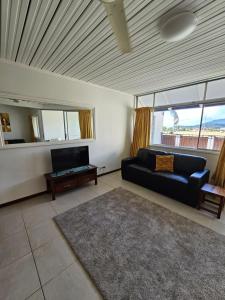 Airlie Seaview Apartments في شاطئ إيرلي: غرفة معيشة مع أريكة وتلفزيون