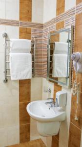 a bathroom with a sink and a mirror and towels at Hotel Status in Vinnytsya