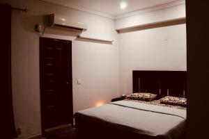 a bedroom with a bed and a black door at Islamabad Holiday Appartments One & Two Bed A Perfect Winter Escape to Murree, Northern Areas & Beyond in Islamabad
