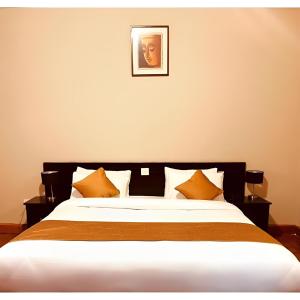 sypialnia z dużym łóżkiem z pomarańczowymi poduszkami w obiekcie Hotel Dorjiling w mieście Paro