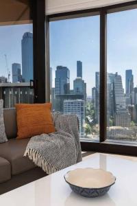 een woonkamer met een bank en een groot raam bij Prima Tower in Melbourne