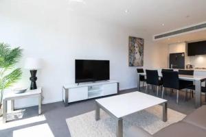 un salon avec une télévision à écran plat sur un mur blanc dans l'établissement Prima Tower, à Melbourne