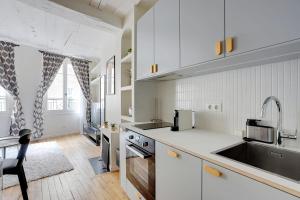 a kitchen with white cabinets and a sink and a table at Saint-Honoré Beautiful apartment 4 people in Paris