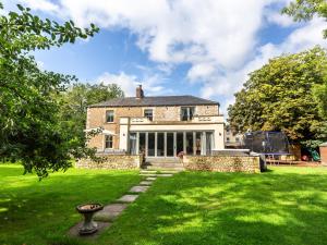 una vieja casa de piedra con césped delante en Vallis Oak Villa en Frome