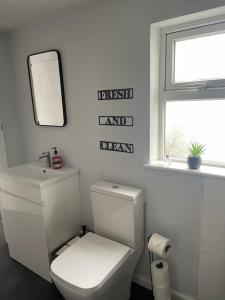 a white bathroom with a toilet and a mirror at The Little Lodge - seaside town of Penarth nr Cardiff in Penarth