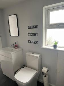 a white bathroom with a toilet and a mirror at The Little Lodge - seaside town of Penarth nr Cardiff in Penarth +14 photos