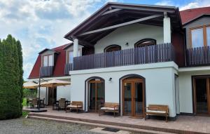 une maison blanche avec des bancs sur une terrasse dans l'établissement Pensiunea Eden Éden Panzió, à Odorheiu Secuiesc