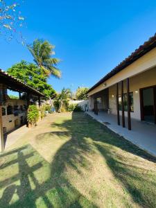 a yard next to a building with a palm tree at Casa com piscina e jacuzzi in Cabo Frio
