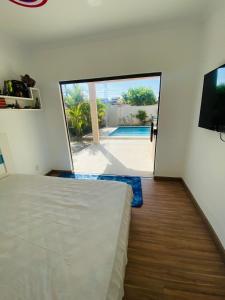 a bedroom with a bed and a sliding glass door at Casa com piscina e jacuzzi in Cabo Frio
