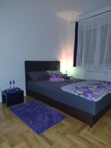 a bedroom with a bed and a purple rug at Apartman Mančić in Pirot