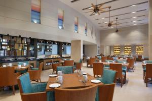 Fairfield by Marriott Goa Calangute في كالانغيُت: غرفة طعام مع طاولات وكراسي خشبية