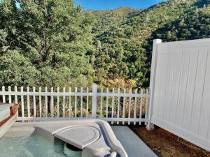 un bain à remous sur une terrasse avec une clôture blanche dans l'établissement Eagle Nest River Views Hot Tub Games Sleeps 6, à Ahwahnee