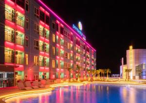 a hotel building with a swimming pool at night at Pentacity Hotel Balikpapan in Balikpapan