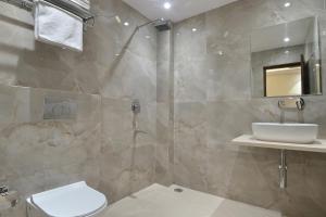 y baño con aseo, lavabo y ducha. en The Saina International - New Delhi - Paharganj en Nueva Delhi