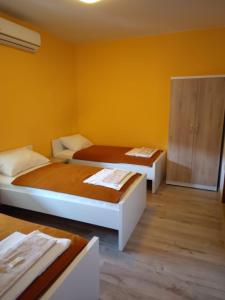 two beds in a room with yellow walls at B&B Nikki in Međugorje